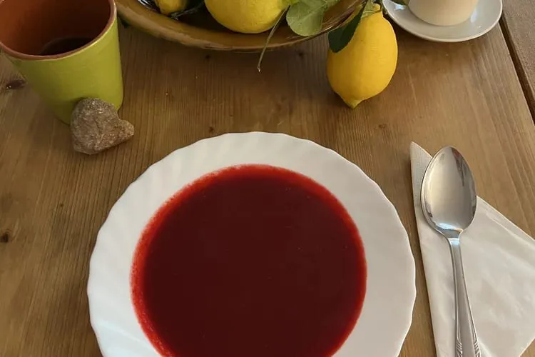Tiefrote Fastensuppe auf einem weißen Teller auf einem Holztisch
